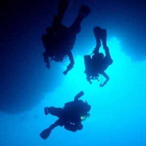 three person diving in the blue ocean